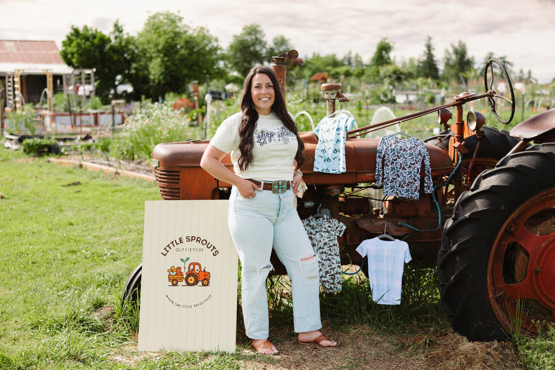 Little Sprouts Outfitters owner standing by rustic tractor with bamboo farm print pajamas and logo branded sign.