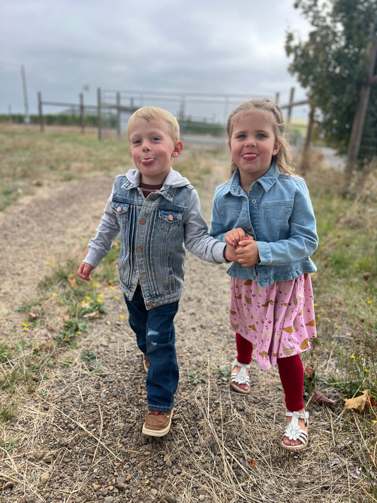 little boy and girl holding hands in a vineyard wearing denim jackets