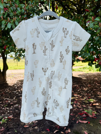 Baby romper with cactus pattern on a hanger against a natural background